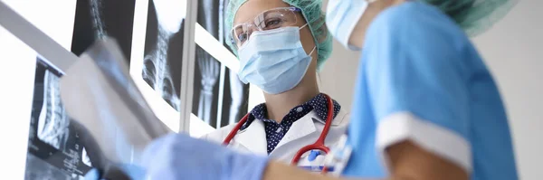 정장을 입은 의사 두 명, 의료용 장갑과 보호용 마스크에는 엑스선 사진이 들어 있다. — 스톡 사진