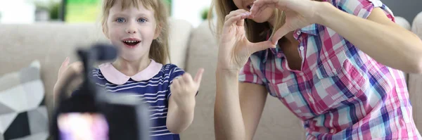 Žena s dítětem sedí na gauči v bytě a ukazuje gesto ruky před kamerou — Stock fotografie