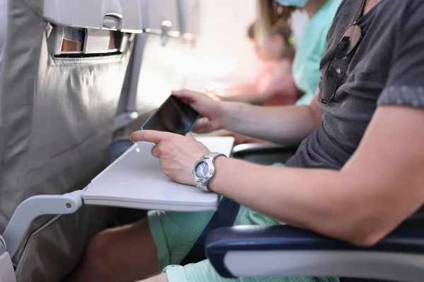 Pasażer samolotu siedzi spokojnie i trzyma telefon w rękach.. — Zdjęcie stockowe