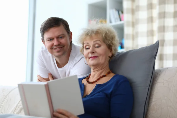 Женщина и мужчина просматривают семейный фотоальбом и улыбаются дома вместе. — стоковое фото