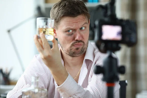 Mann mit blauem Auge filmt Videoblog verkostet Alkohol für Qualität. — Stockfoto