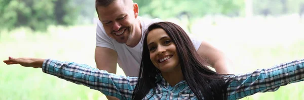 Femme est assise dans un fauteuil roulant souriant avec ses bras écartés homme roule. — Photo