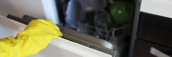 Hand in Hand mit gelbem Handschuh öffnet Spülmaschine in Großaufnahme — Stockfoto