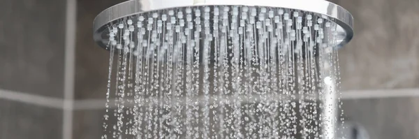 Gros plan sur le flux d'eau de la pomme de douche à effet pluie dans la salle de bain — Photo