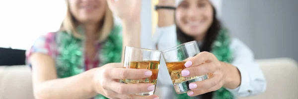 Frauen mit Neujahrsschmuck und Weihnachtsmannmützen halten Gläser mit Alkohol in der Hand in Großaufnahme und winken — Stockfoto