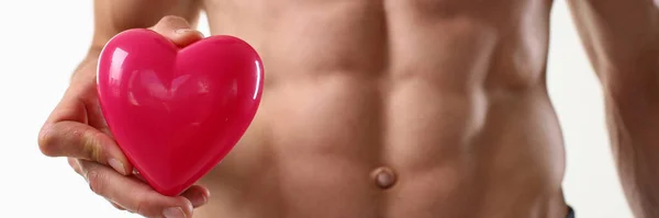 Jeune homme athlétique avec abdos parfait tenant coeur rose — Photo