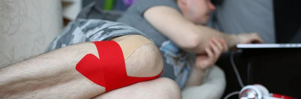 Молодий чоловік з травмованою ногою лежить на дивані — стокове фото