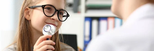 Adorável menina brincando médico com estetoscópio na clínica — Fotografia de Stock