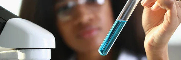 Женщина-врач держит пробирку с голубой жидкостью — стоковое фото