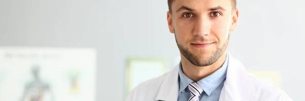 Handsome young doctor standing in modern clinic — Stock Photo, Image