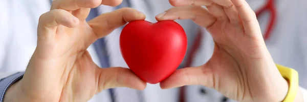 Doctors cardiologists hold red toy heart in clinic closeup — Stock Photo, Image