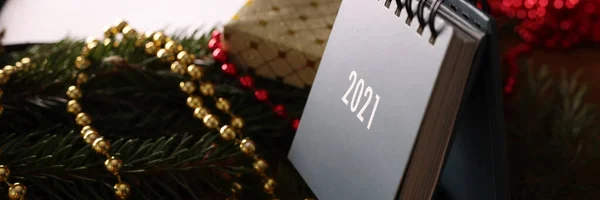 Volný list kalendář stojí na dřevěném stole mezi větvemi vánočního stromku a dekorace — Stock fotografie