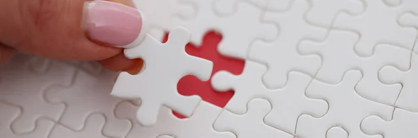 Womans hand placing last piece of puzzle on table closeup