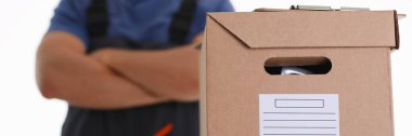 Önlüklü bir adam kartonla paket getiriyor.