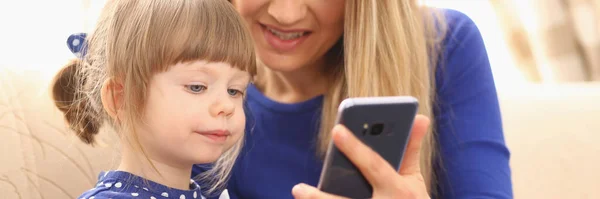 Schattig klein meisje met lachende moeder met behulp van smartphone — Stockfoto