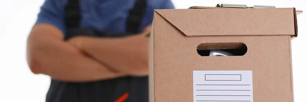 Man in working apron bringing parcel in cardboard — Stock Photo, Image