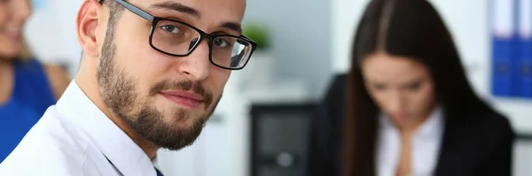 Guapo hombre barbudo sonriente trabajando con colegas en la oficina — Foto de Stock