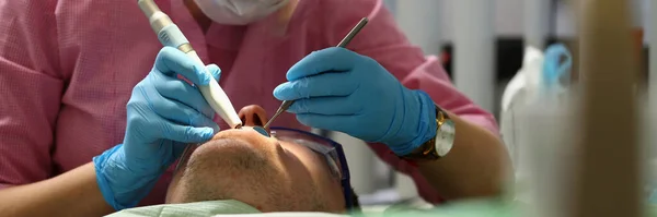 Geconcentreerde jonge tandarts doet tanden controle in de kliniek — Stockfoto