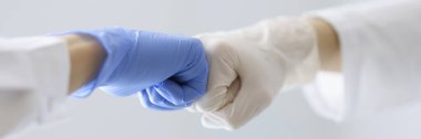 Plastik eldivenli doktorlar klinikte yumruklarına dokunuyor.