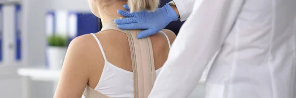 Doctor puts back brace on patient closeup