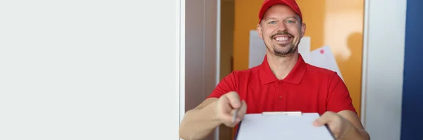 Sorrindo mensageiro masculino mantém a área de transferência e caneta. — Fotografia de Stock