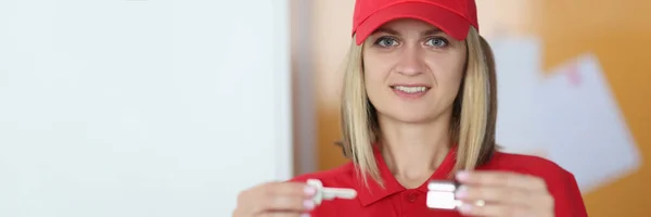 Mujer en uniforme rojo sostiene una llave y un candado en sus manos. — Foto de Stock