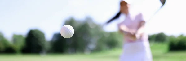 Golf ball against background of hitting woman closeup — Stock Photo, Image