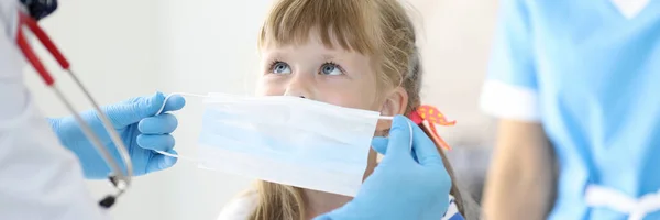 Ärztin mit kleinem Kind setzt Schutzmaske auf — Stockfoto