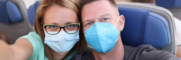 Férj és feleség szelfit készítenek a repülőn orvosi maszkban. — Stock Fotó