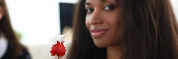 Junge Frau zeigt Erdbeeren mit Sahne in Großaufnahme — Stockfoto