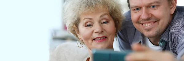 Adult son shows mother a photo in the phone — Stock Photo, Image