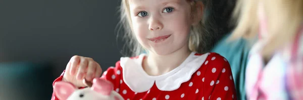 Щаслива маленька дівчинка кладе монети в скарбничку — стокове фото