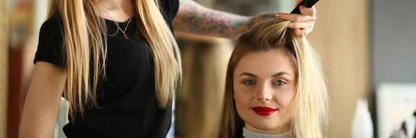 Cabeleireiro separando cabelos longos de uma jovem cliente feminina — Fotografia de Stock