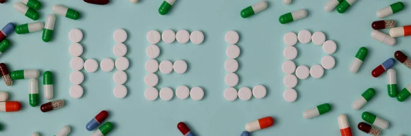 Word Help landing out from white pills as on background of multi-colored capsules — Stock Photo, Image