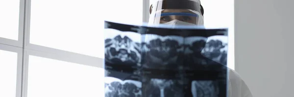 Läkare i skyddsdräkt med röntgenbild på kliniken — Stockfoto