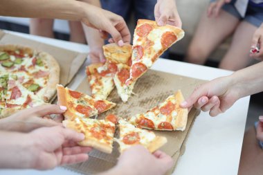 Yetişkinler ve çocuklar bir dilim pizzayı kutuya koyarlar.