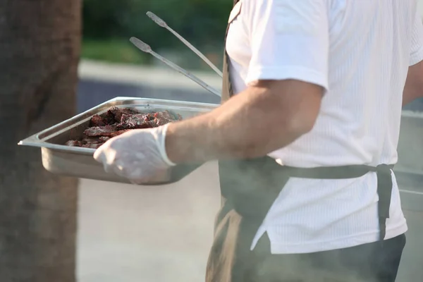 Aşçı ızgara etle birlikte yemek tepsisi taşır. — Stok fotoğraf