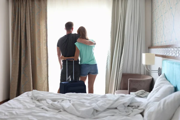 Kadın ve erkek, valizin yanındaki pencerenin yanında birbirlerine sarılıyorlar.