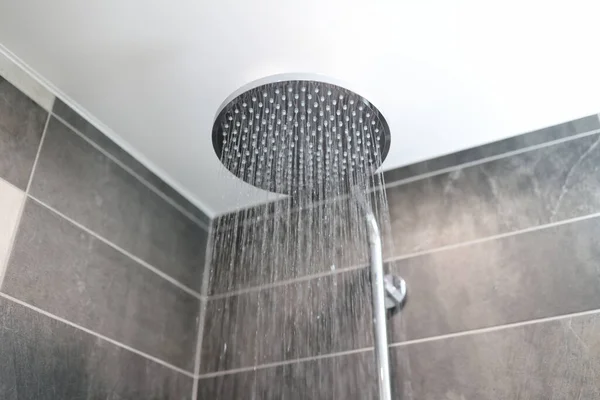 No banheiro, a água flui da torneira do chuveiro — Fotografia de Stock