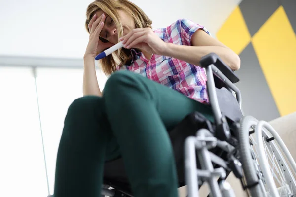 Жінка в інвалідному візку дивиться на тест на вагітність — стокове фото