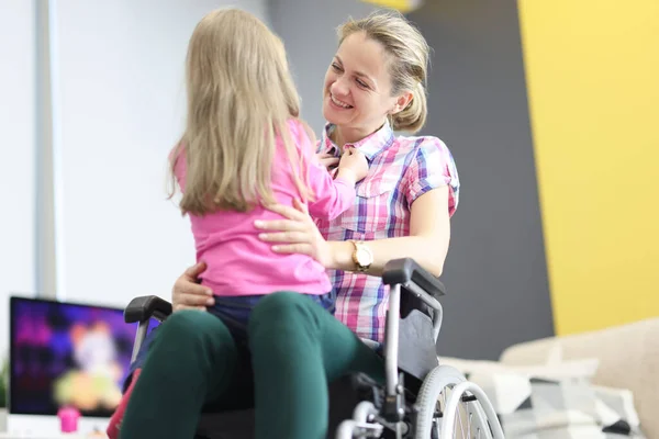 Усміхнена жінка в інвалідному візку обіймає маленьку дівчинку — стокове фото