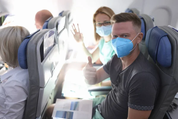Mężczyzna i kobieta w medycznych maskach ochronnych na pokładzie samolotu — Zdjęcie stockowe