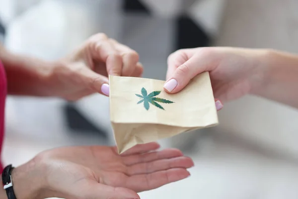 Entregar sobre saco de papel com sinal de maconha. — Fotografia de Stock