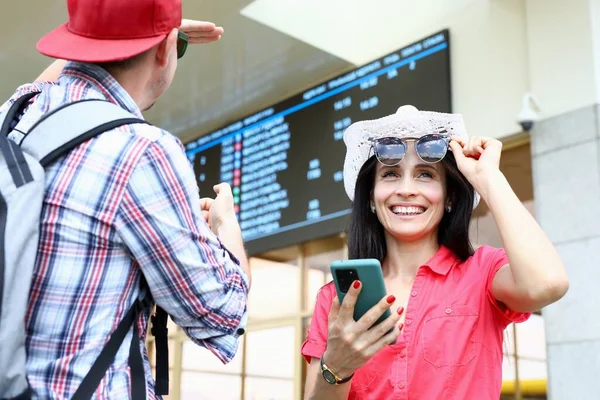 Man and woman under an information board with smartphone — Stock Photo, Image