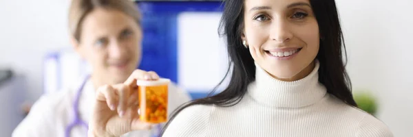 Mujer médico y paciente están sonriendo y sosteniendo frasco de píldoras — Foto de Stock