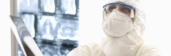 방사선 촬영 장비를 손에 들고 바닥에 뿌려진 항 염병 방지 슈트를 입고 있는 피곤 한 의사 — 스톡 사진