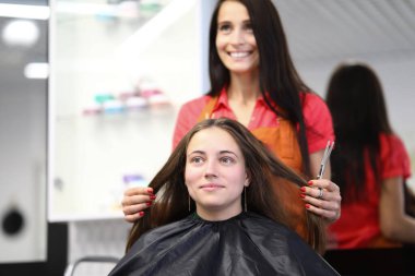 Kuaför müşterinin saçını güzellik salonunda tutuyor.