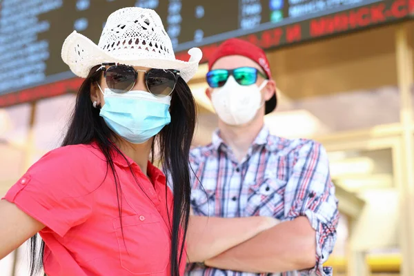 Havaalanındaki bir bilgi panosunun altında tıbbi koruyucu maskeli kadın ve erkek portresi. — Stok fotoğraf