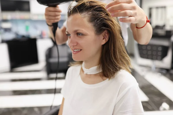 Femme dans un salon de beauté sécher sa tête avec sèche-cheveux — Photo