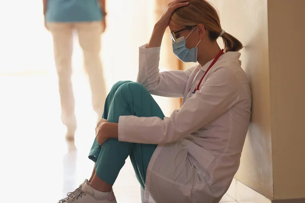 Medico frustrato siede in primo piano corridoio dell'ospedale — Foto Stock